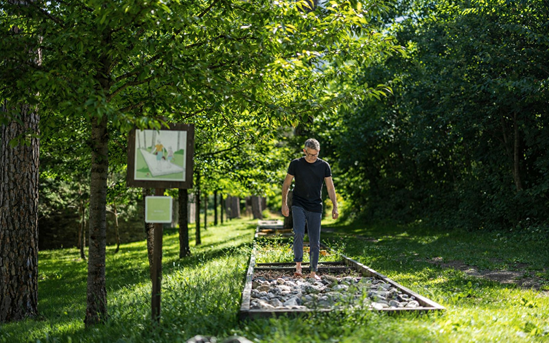 Person unterwegs auf dem Sinnesweg in der Parkanlage der Klinik Beverin