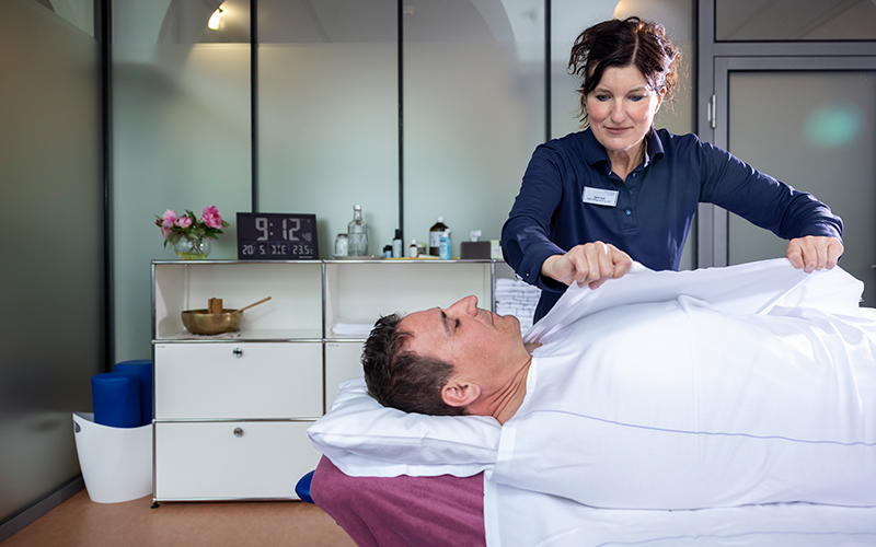 Behandlung mit Wickel bei einer liegenden Person