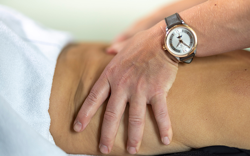 Manuelle Behandlung am Rücken einer liegenden Person