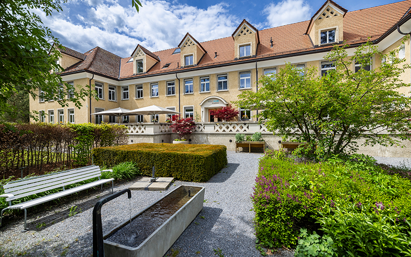 Garten der Privatklinik MENTALVA mit Klinikgebäude im Hintergrund