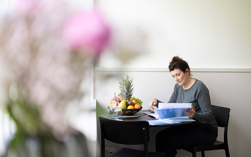 Patientin beim Lesen am Tisch in einem Privatzimmer der Privatklinik MENTALVA.